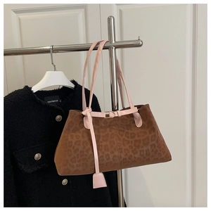 Detail of leopard print tote bag with pink straps and decorative metal buckles