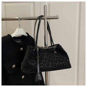 Detail view of large leopard print handbag hanging on a silver metal coat rack