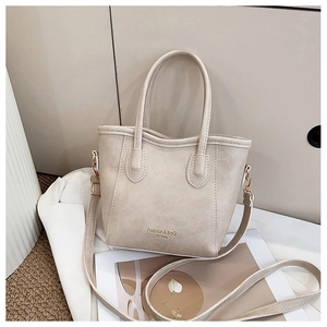 Detailed macro view showing the fine leather texture and golden logo print on the beige tote