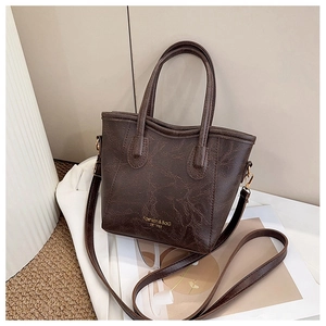 Detailed shot of dark brown wrinkled leather texture and gold hardware on tote bag