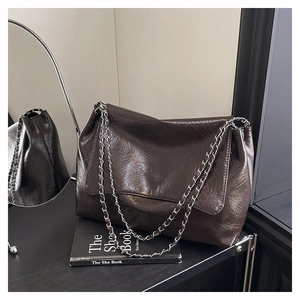 Vue détaillée du sac cabas marron foncé avec texture craquelée brillante et chaînes