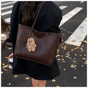 Detail view of large dark brown retro tote bag in PU leather with a plush bear charm