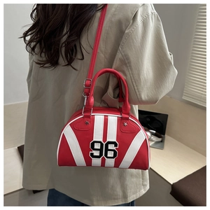 Dettaglio borsa bowling rossa con patch 96 e tracolla rimovibile su modella in trench