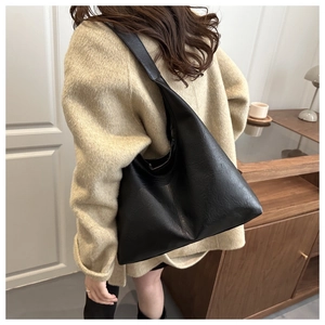 Modern black large-capacity hobo bag with leather texture styled on a model's shoulder