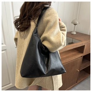 Close-up of a large black vintage textured leather tote bag on a model shoulder