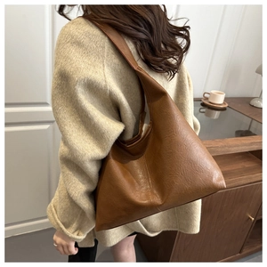 Detail shot of caramel brown faux leather hobo bag showing wide strap and smooth texture