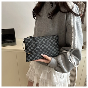 Detail view of rectangular envelope bag with white M-logo print and wristlet strap