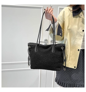 Detail view of the black fuzzy plush tote bag with slim leather straps and metal buckle