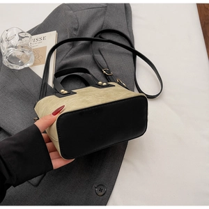 Détail d'un mini sac vintage en toile beige avec bordure en cuir noir et rivets dorés