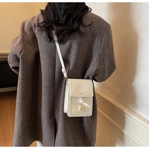 Detail showing the white PU leather crossbody phone bag on a model in a grey blazer