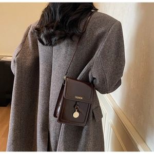 Close-up of deep brown glossy leather mobile phone bag with golden fashion letter details