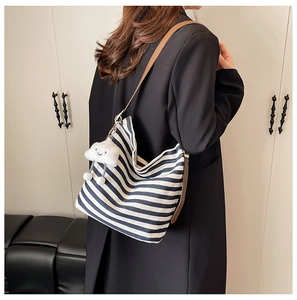 Detail of blue and white striped canvas tote with brown leather strap and cloud charm