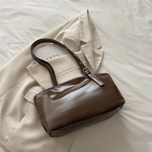Détail d'un sac sous le bras en cuir marron foncé brillant avec boucle réglable argentée