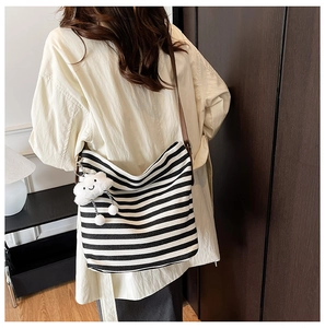 Rear view of striped canvas tote bag with brown leather strap and cloud charm detail