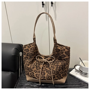 Détail d'un sac cabas léopard avec un nœud en cuir et des bandoulières en PU beige