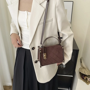 Quilted dark brown retro crossbody bag with golden clasp shown on a model in minimalist style