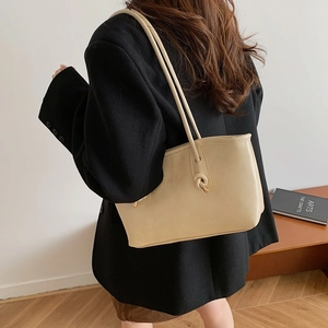 Large cream leather tote bag with unique knot design and gold hardware on shoulder