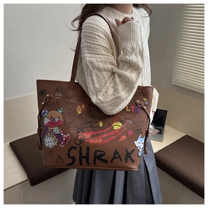 Gros plan sur sac seau marron avec graffiti d'ours et détail de cordon sur pull blanc