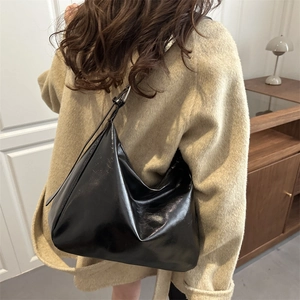 Minimalistische glänzende schwarze Hobo-Tasche für Damen, kombiniert mit einem Wollmantel