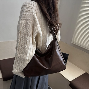 Retro dunkelbraune große Hobo-Tasche getragen von einem Modell in einer minimalistischen Szene