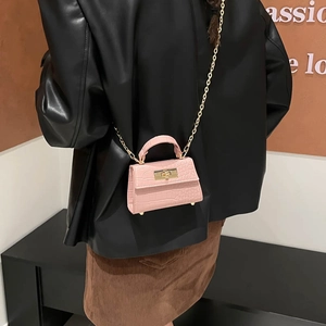 Pink croc-embossed mini handbag with gold chain strap worn by a model in a trendy style