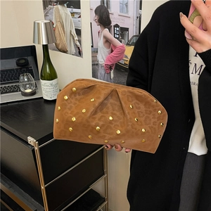 Brown leopard print pleated clutch bag with golden rivets held in a home setting