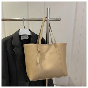 Détail du sac cabas beige clair avec poche avant et bandoulière à boucle dorée réglable