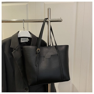 Détail d'un cabas noir minimaliste avec texture en similicuir et boucle en métal doré