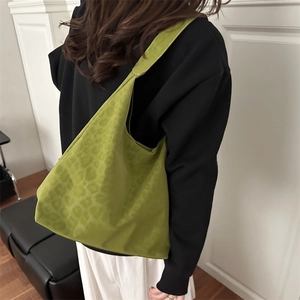 Green leopard print hobo tote bag worn by a model in a bright minimalist interior