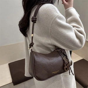 Retro dark brown leather shoulder bag with knotted strap and vintage metal pendant