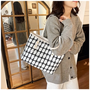 Detalle de bolso tote a cuadros con botones dorados y finas correas de cuero blanco
