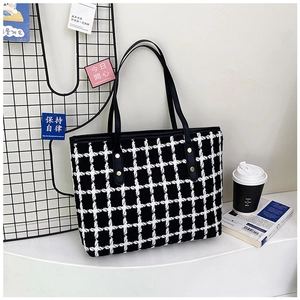 Detalle del bolso tote de lona a cuadros con asas de cuero negro y remaches dorados