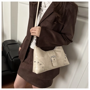 Detail of beige rivet tote bag with metallic buckle and glossy finish texture