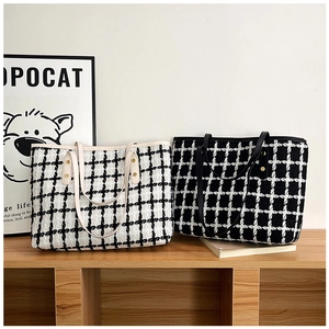 Detalle de bolsos tote de tweed a cuadros con remaches de metal en un estante