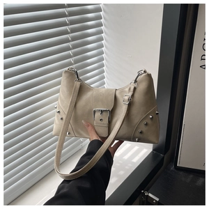 Detail of beige tote bag with silver studs and adjustable strap on a minimalist background