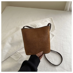 Detail of dark brown suede bucket bag featuring premium texture and soft leather strap