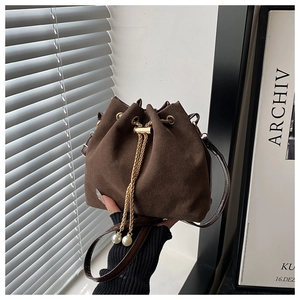 Détail du sac seau en daim marron avec cordon en chaîne dorée et breloques en perles