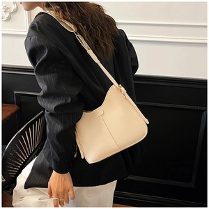 Gros plan sur un sac hobo beige avec large bandoulière et détails en cuir