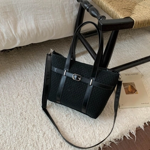 Close-up of retro black bucket bag showing tweed and leather texture on a woven chair