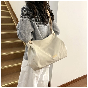 Detail of a large cream tote bag with brown leather straps shown on a model