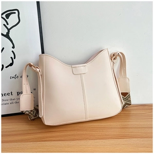 Détail du sac seau en cuir blanc cassé avec une large bandoulière à motif ethnique