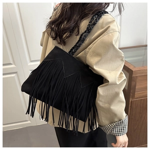 Detail of black bohemian tassel bag with woven shoulder strap and suede fringe textures