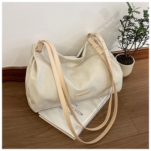 Close-up of a minimalist cream white large tote bag placed on an art book with soft lighting