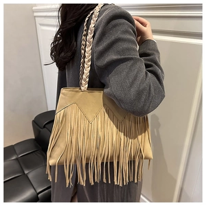 Detail of camel suede tote bag featuring long fringes and braided shoulder straps