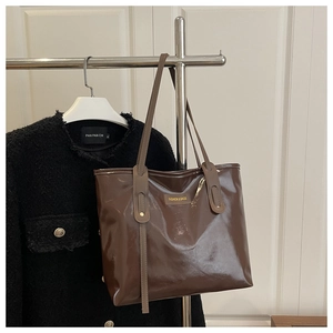 Detail of a brown patent leather tote bag with FASHION & BAGS tag and slim shoulder straps