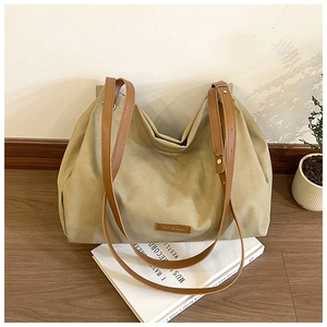 Detail view of khaki large tote bag with brown straps and brand tag on books