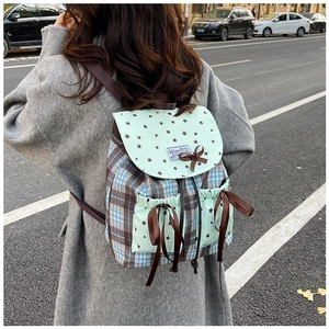 Detailed outdoor shot of green plaid backpack with star prints and bowknot pockets
