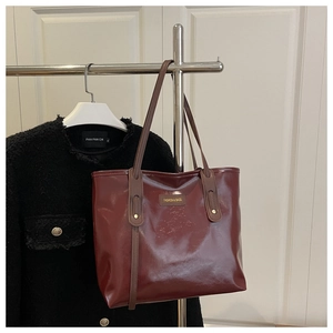 Macro detail of wine red PU leather tote bag with glossy finish and fashion logo