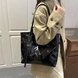 Large black patent leather tote bag with glossy finish and slim shoulder straps for women