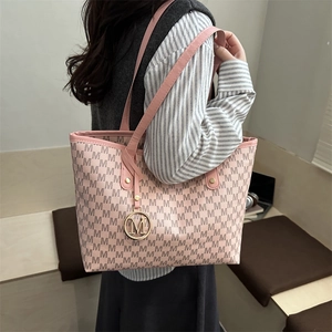 Sac fourre-tout rose avec motif M et pendentif doré porté par un mannequin en intérieur